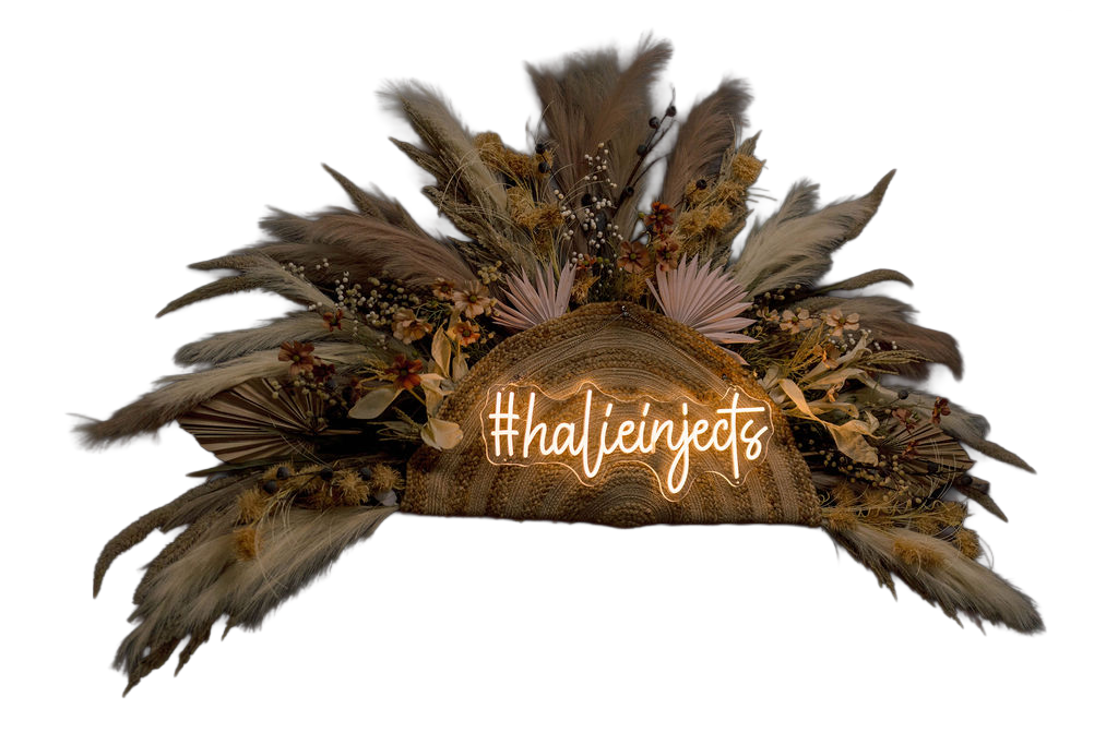 Rustic floral arrangement with neon sign reading #halieinjects on dark background.