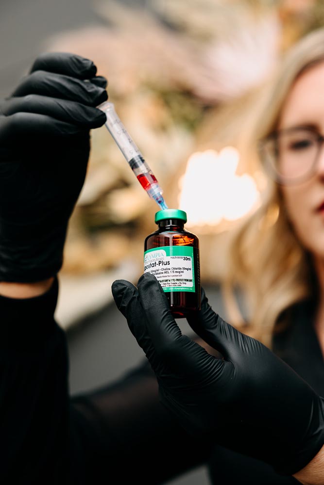 A person holding a syringe and vial labeled lipostat-Plus with gloved hands.