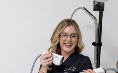 A woman holding a BBL HERO device, smiling during a cosmetic procedure demonstration.