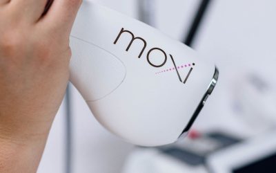 Hand holding Moxi laser device for skin treatment in a clinic setting.