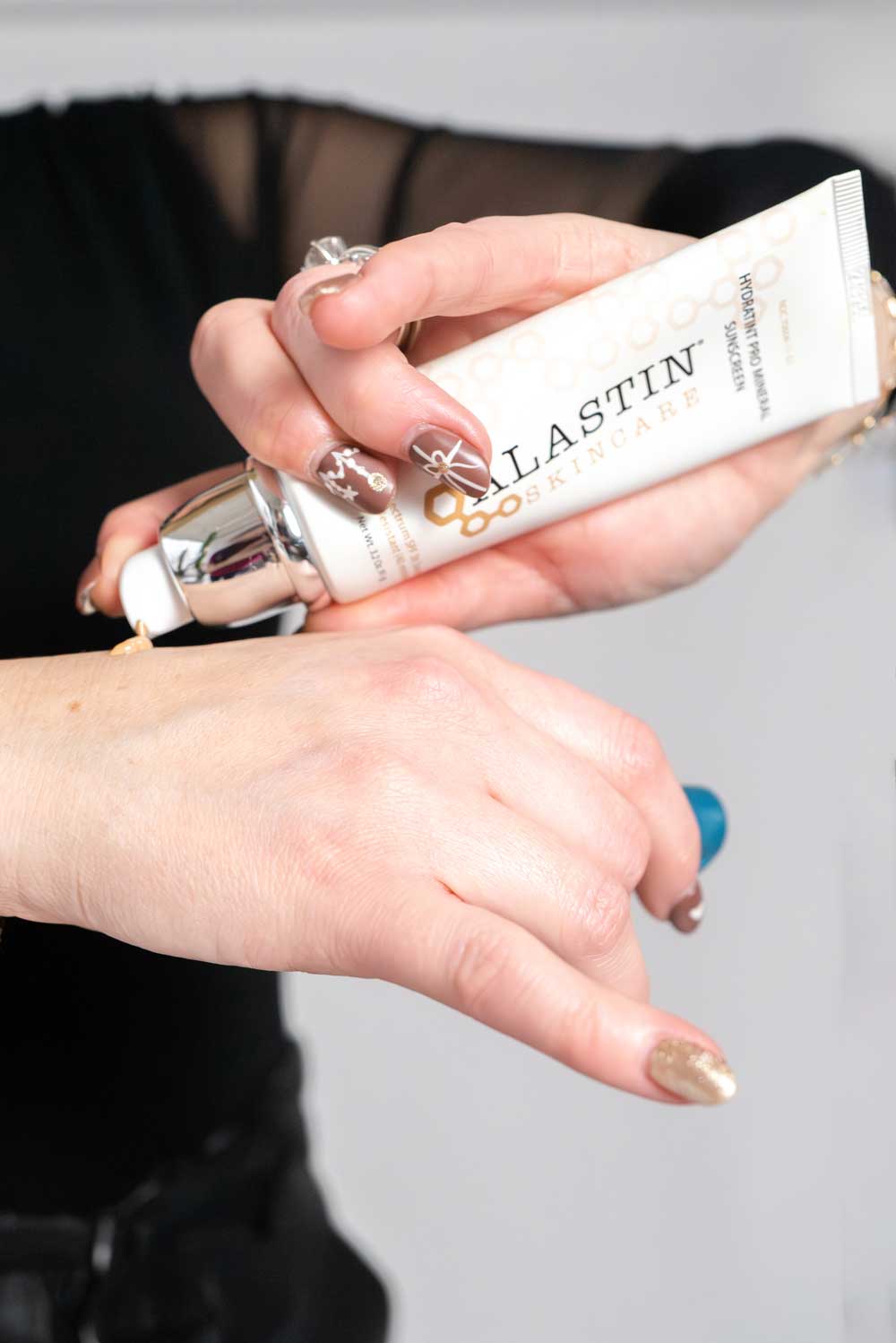 Applying Alastin Skincare Hydratint Pro Mineral Sunscreen to hand.