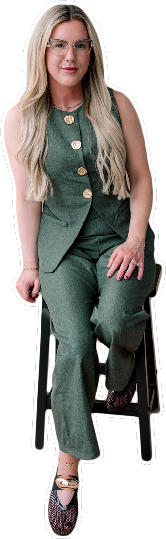 A woman with long blonde hair in a green suit sits on a stool.