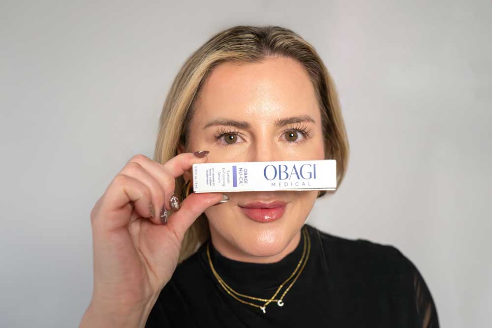 Person holding Obagi Medical product box in front of face, focusing on skincare branding.
