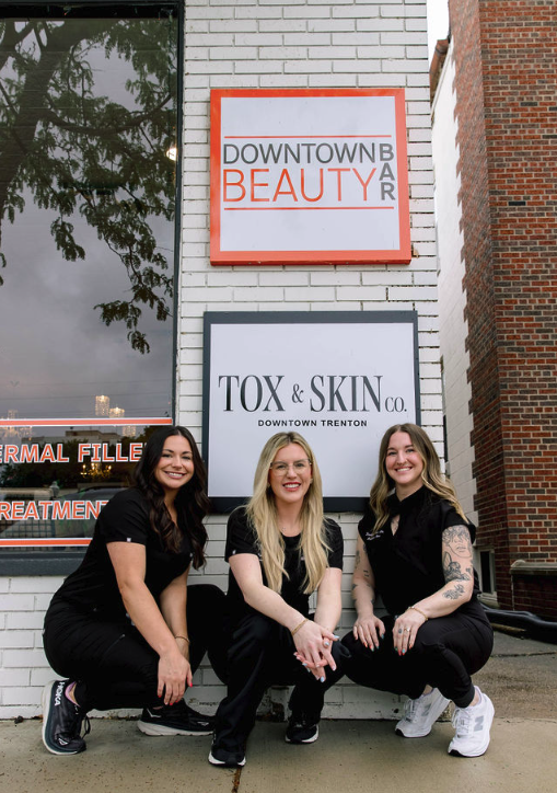 Three women in black outfits outside Downtown Beauty Bar and Tox & Skin Co. signs.